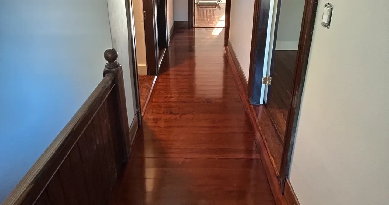 Refinished red oak hardwood hallway with rich amber stain and original dark-wood wainscoting
