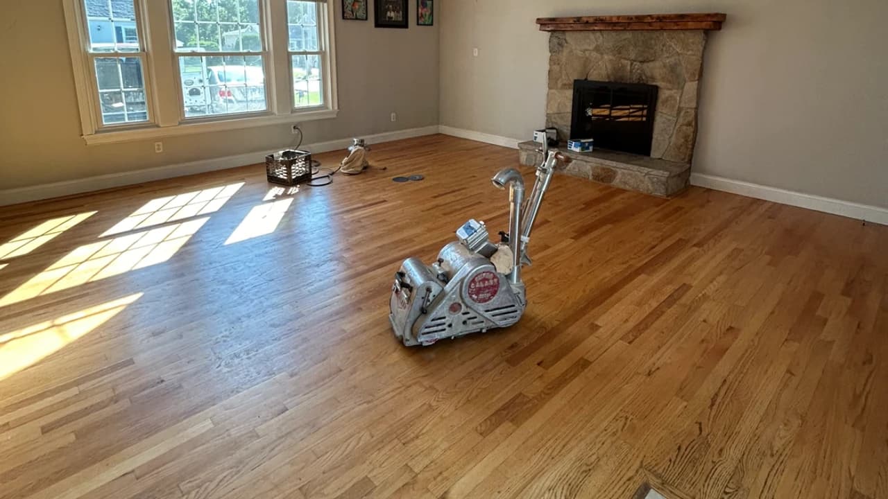 Polishing buffer on a refinished hardwood floor near a stone fireplace