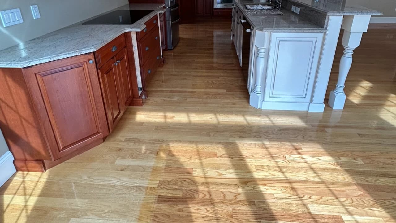 Refinished red oak hardwood floor in a kitchen with wooden cabinets and granite island